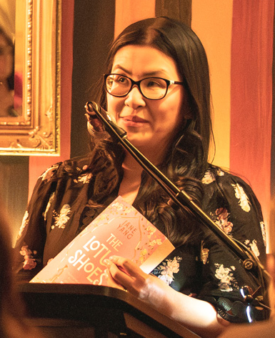 Image is author Jane Yang holding up her debut novel, The Lotus Shoes.